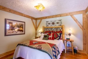 a cozy bed in a rustic cabin style - Room 2 at the Hemlock Inn